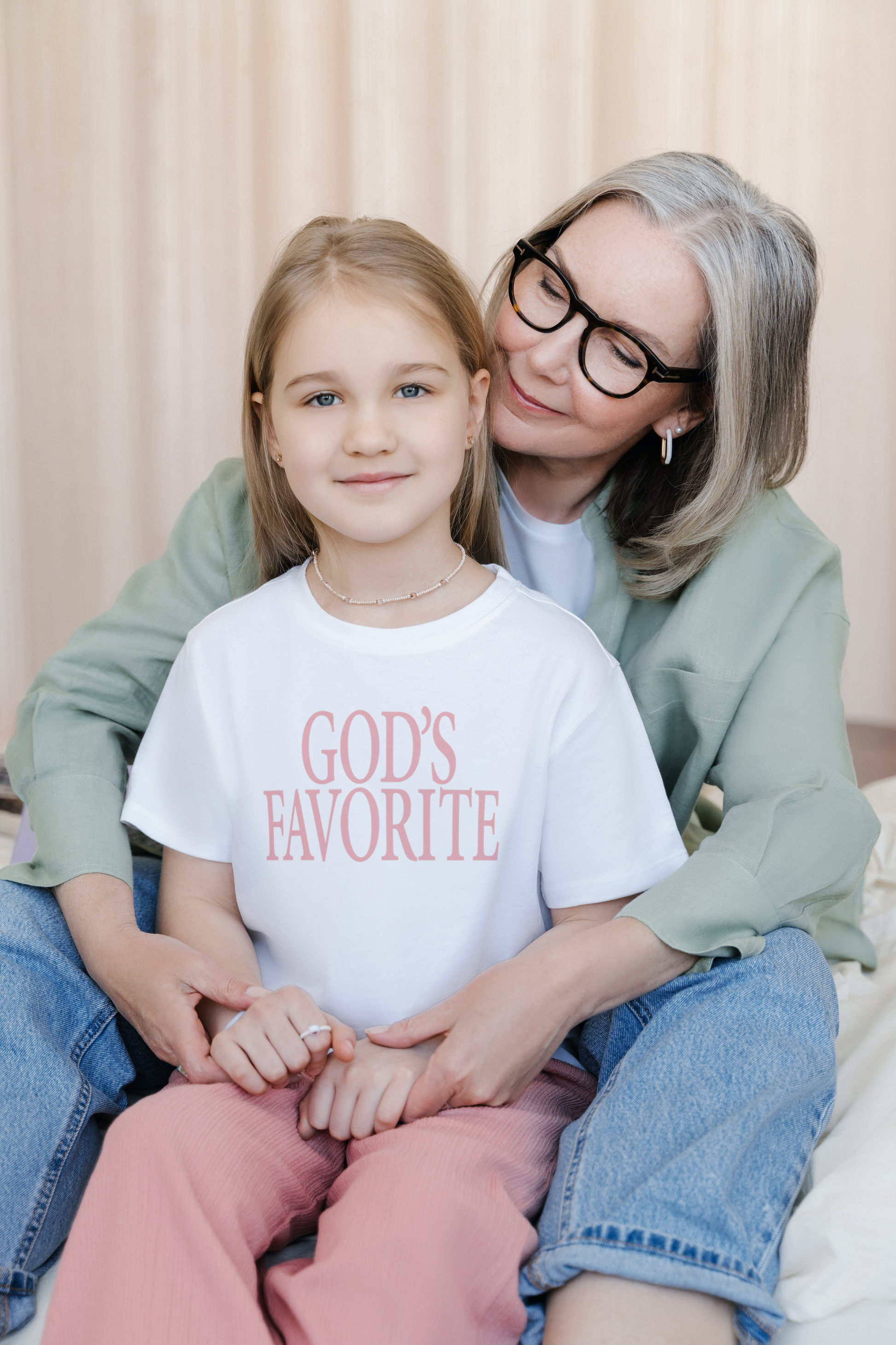 Little girl wearing a God's Favorite T-shirt beside her mother